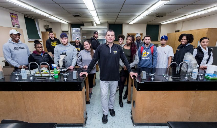 classroom lab with students and professor posing at lab tables