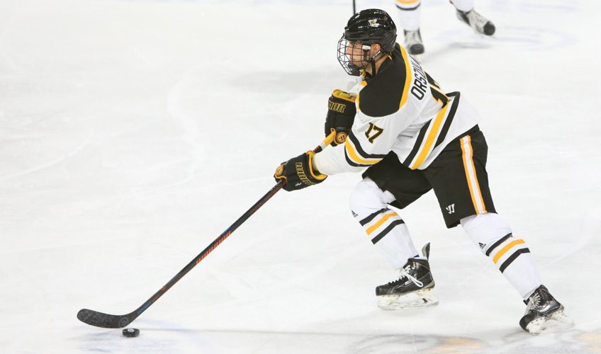 Former AIC Ice Hockey Captain and Professional Ice Hockey Player Austin Orszulak skating with puck