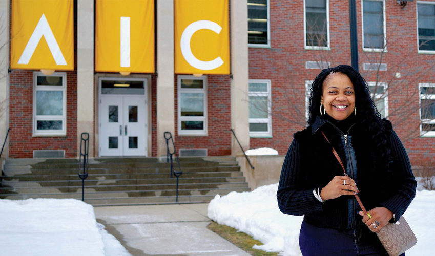Alum Shanetia Capman standing in front of Amaron Hall banners